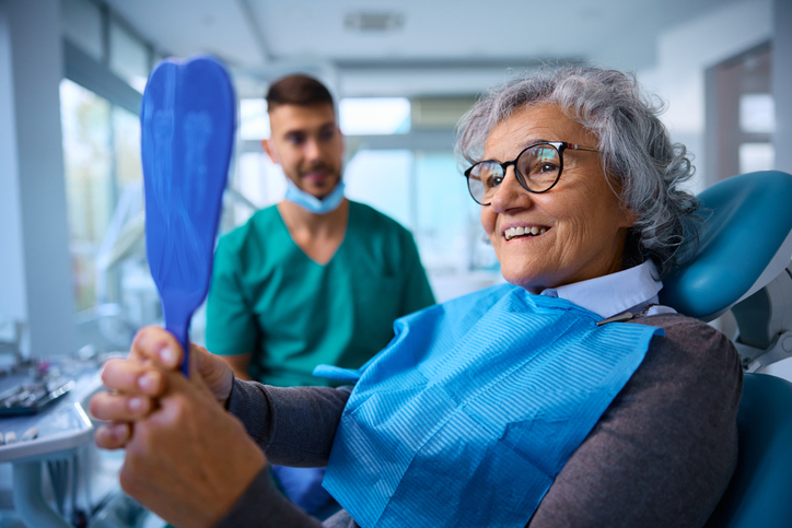 Female patient checking her teeth after a periodontist treatment