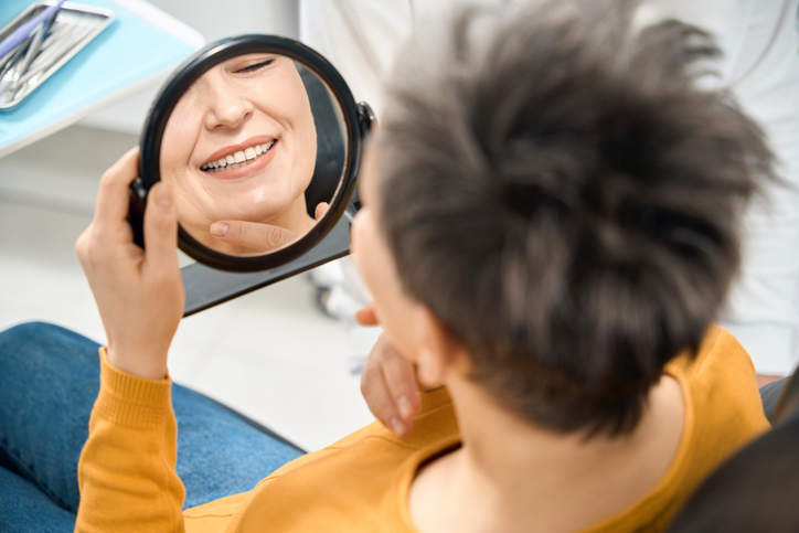 Female patient in dental chair looking at dental implant