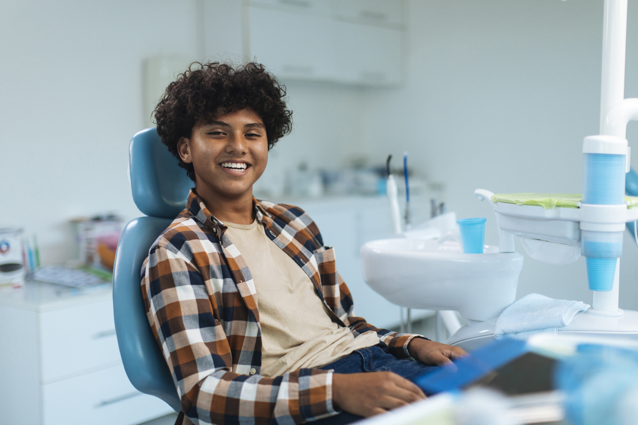 A male teenager sitting in a dental chair smiling