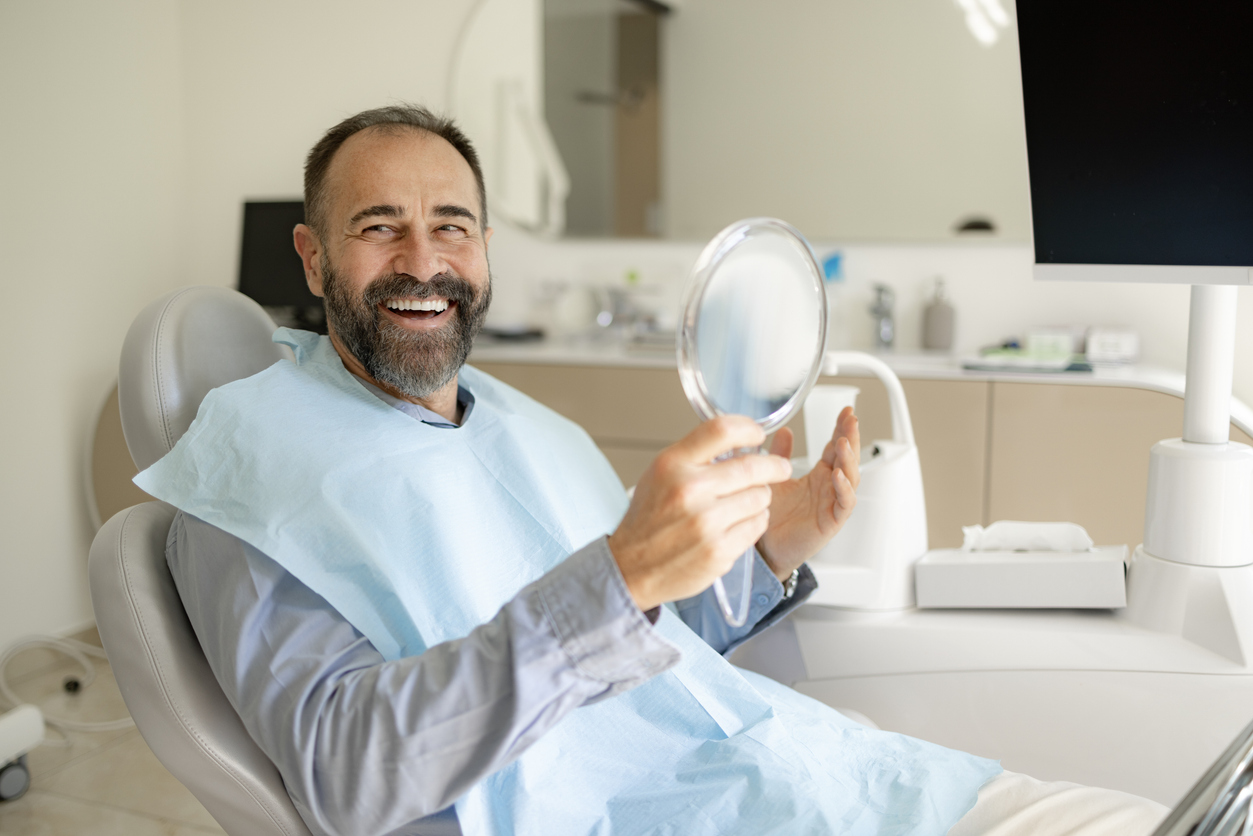 Happy man with teeth-in-a-day implants in dental chair